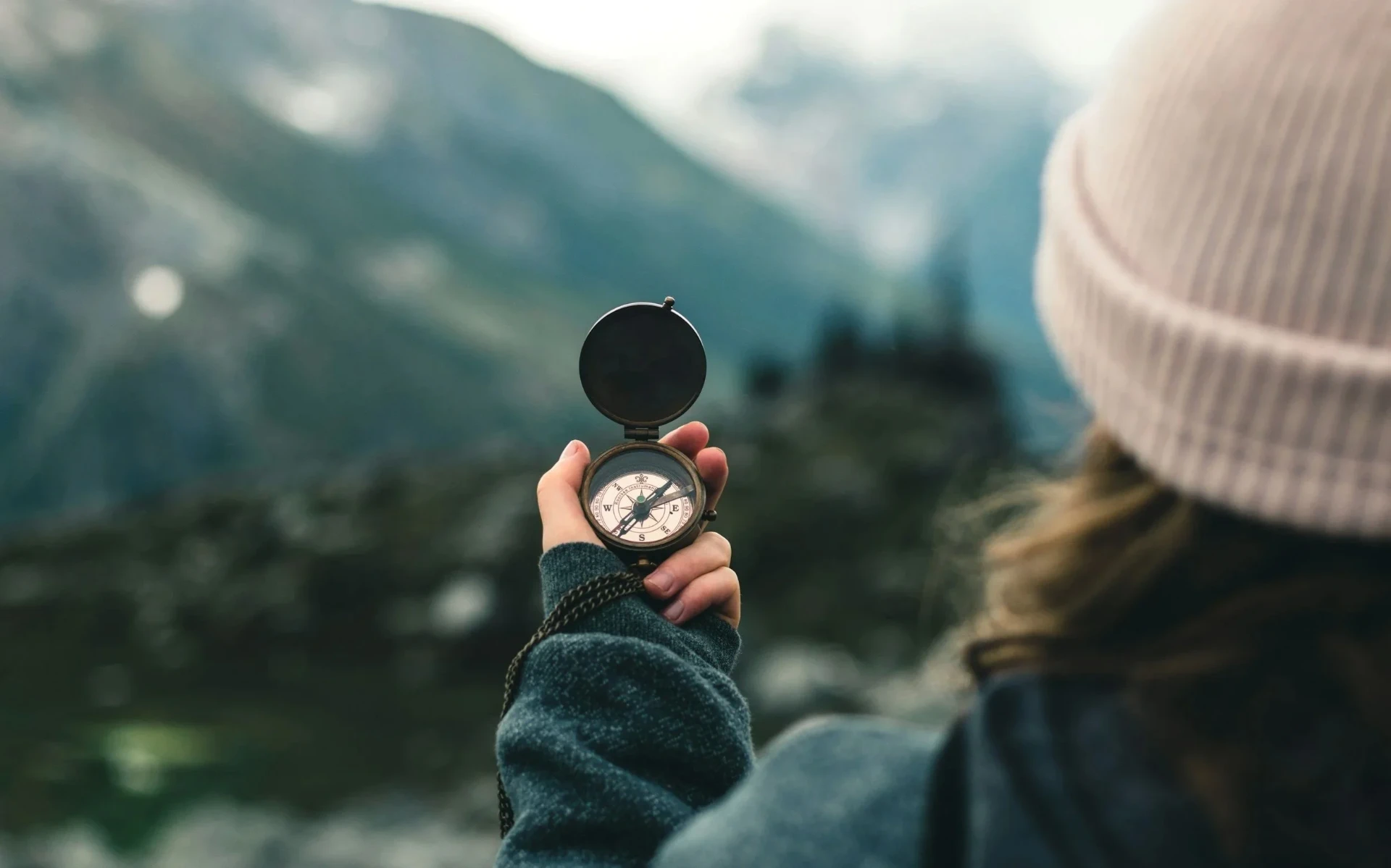 A hand holding a compass at sunset